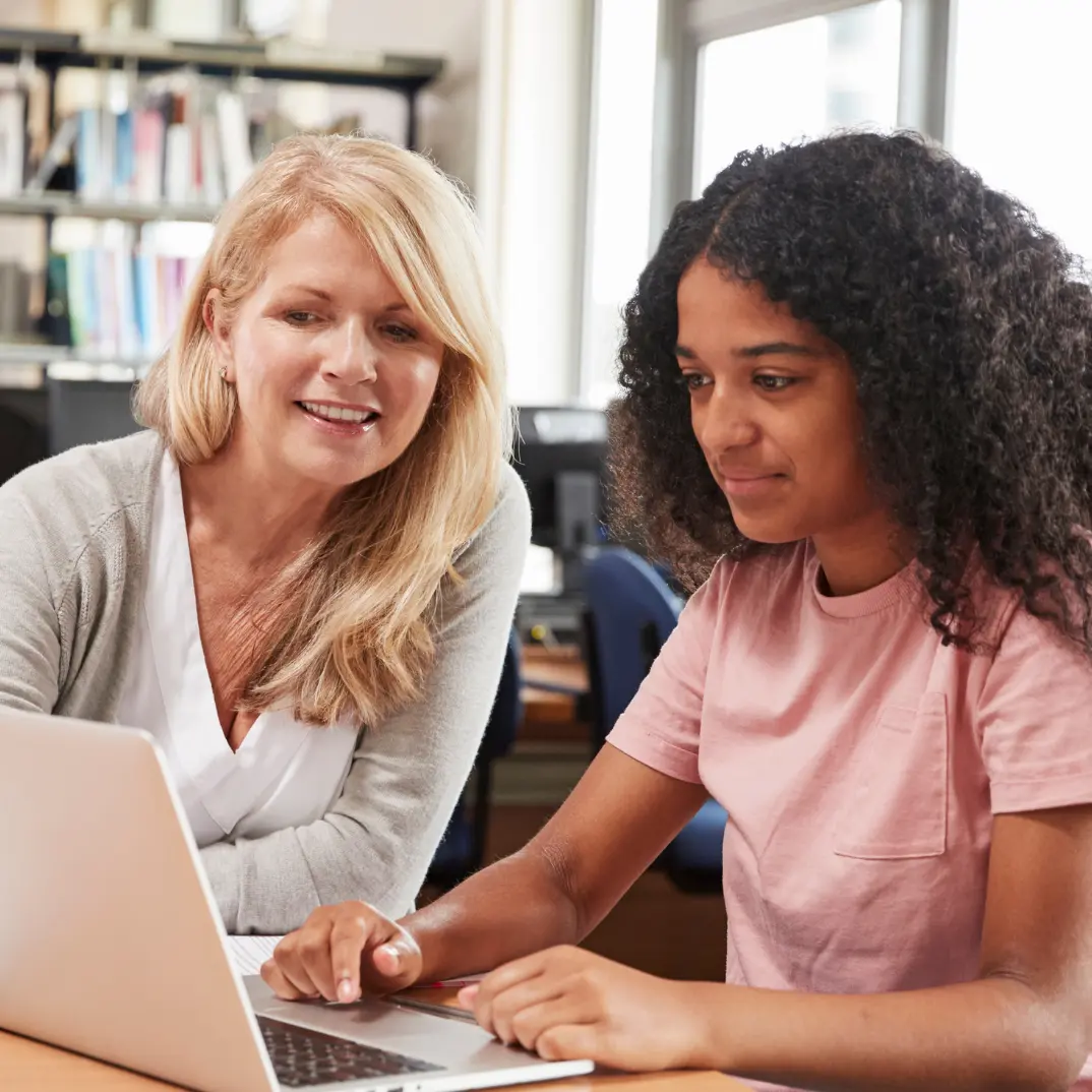Teacher helping a student doing work on her laptop